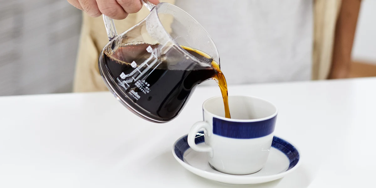 コーヒーサーバーからカップへ淹れたてのコーヒーを注ぐ様子