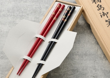 桐箱にセットされた、黒と赤の桜柄の塗り箸