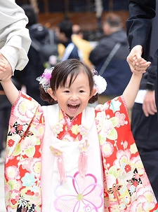 七五三の着物を着て万歳する笑顔の女の子