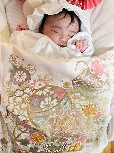 華やかな産着に包まれて眠っている赤ちゃん