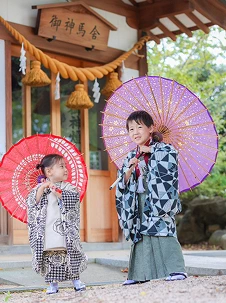 和傘を差して社殿の前に立つ七五三の子供たち