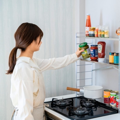 棚に手を伸ばす女性