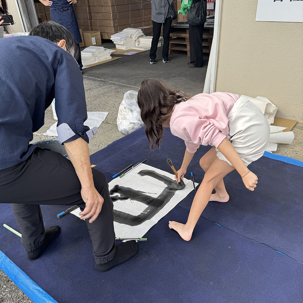 子どもが大きな筆で書道を体験する様子